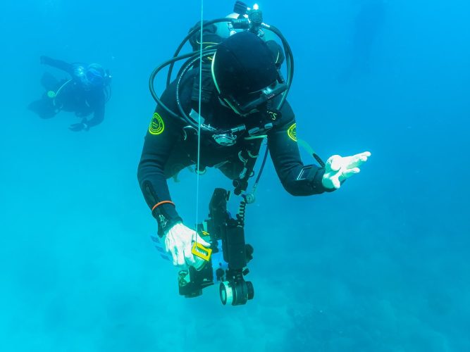 Dan Lindsay rehearses an emergency ascent using a Surface Marker Buoy (SMB) while carefully monitoring his depth — a critical safety procedure in the Galápagos, where powerful currents and shifting surface conditions make SMB deployment mandatory for divers. These volcanic islands, formed along the Nazca Plate hotspot off Ecuador’s coast, sit at the crossroads of major Pacific currents including the cold Humboldt, the deep‑rising Cromwell, and the warm Panama Current. In such dynamic waters, precise buoyancy control and a clearly visible SMB are essential for safe surfacing and for ensuring dive vessels can track ascending divers. Dan Lindsay practicing an emergency ascent while deploying a Surface Marker Buoy and monitoring his depth in the strong‑current waters of the Galápagos Islands.
